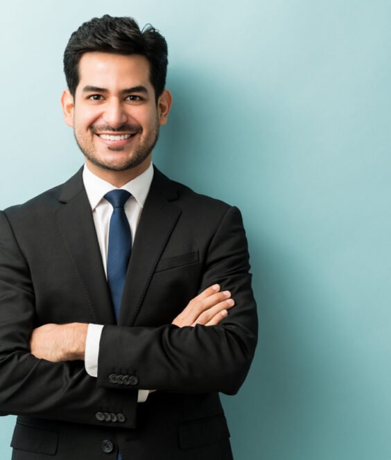 Handsome Hispanic Businessman In Black Suit Smiling young male professional standing with arms crossed while making eye contact against isolated background